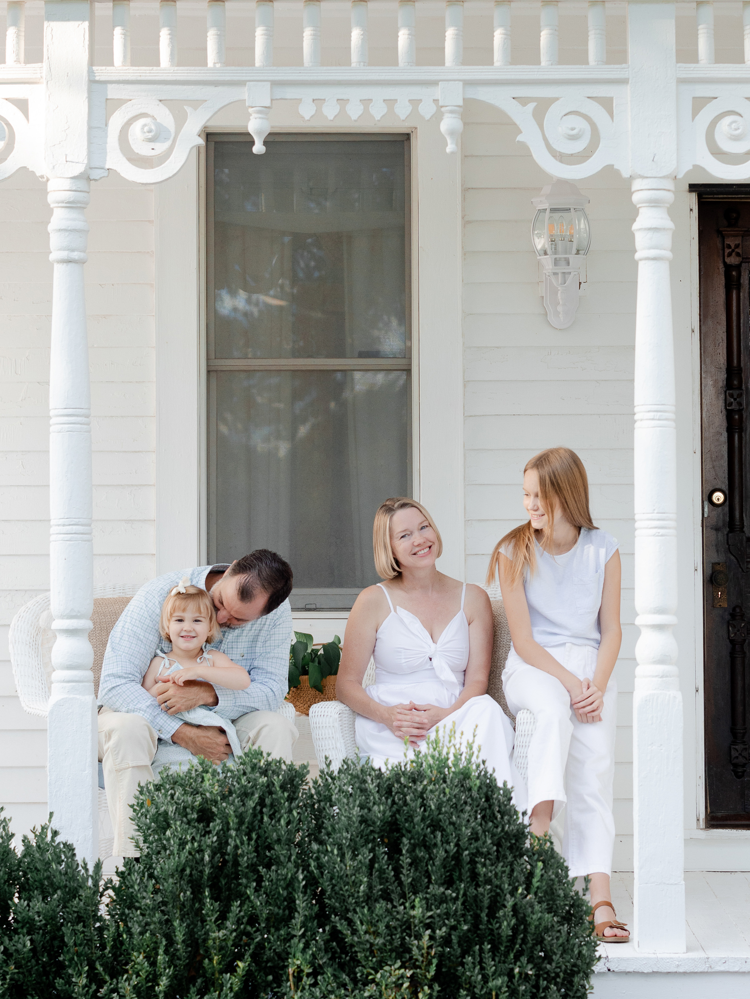 Parents and daughters smiling on white wicker chairs — Love Tree Studios family photography in Missouri.