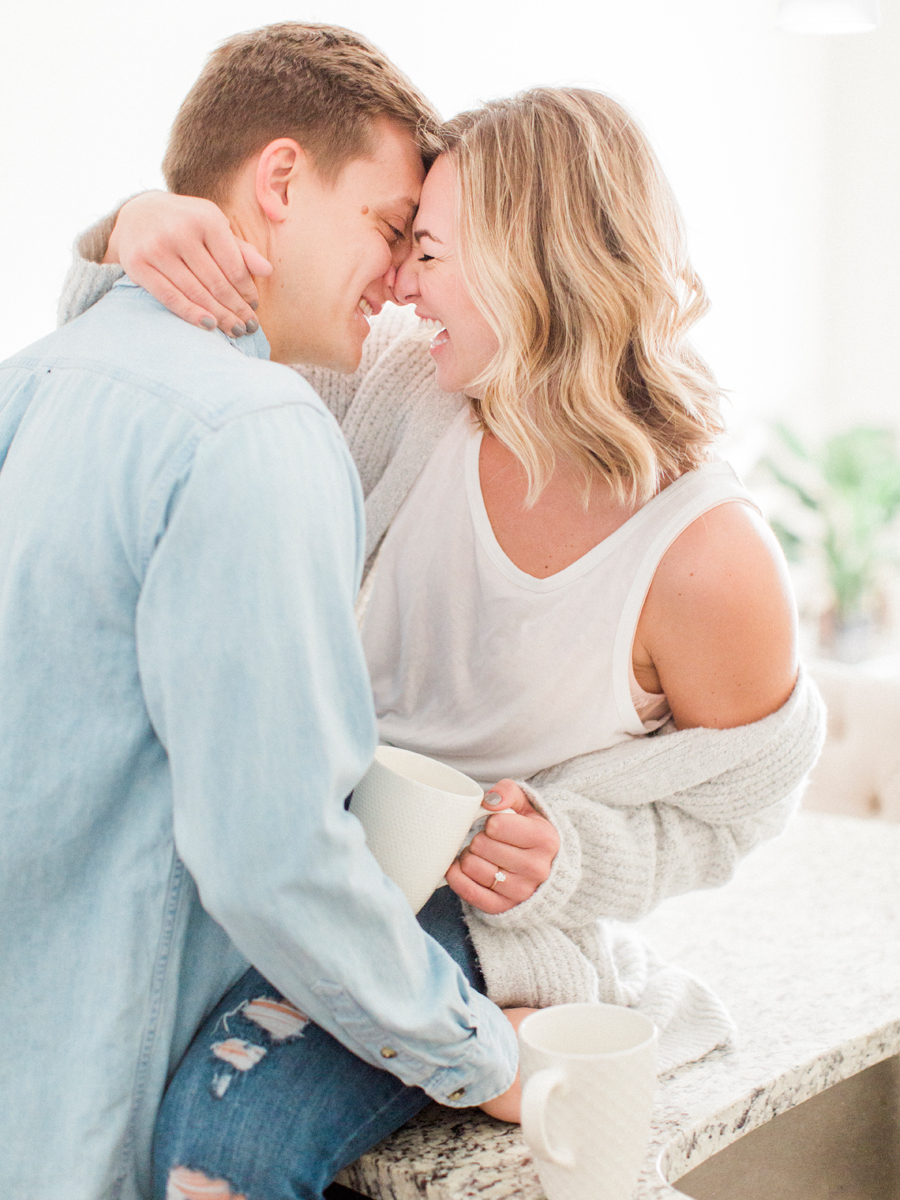 A couple laughs at their intimate in-home engagement session by Missouri photographer Love Tree Studios.