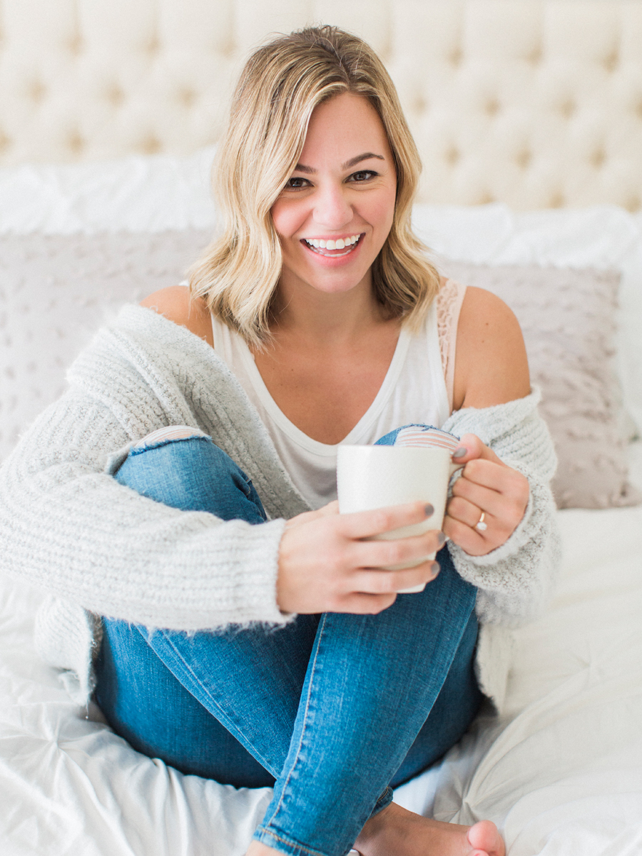 A girl poses with her coffee on the bed during her itimate in-home engagement sesion in Columbia Missouri by Love Tree Studios.
