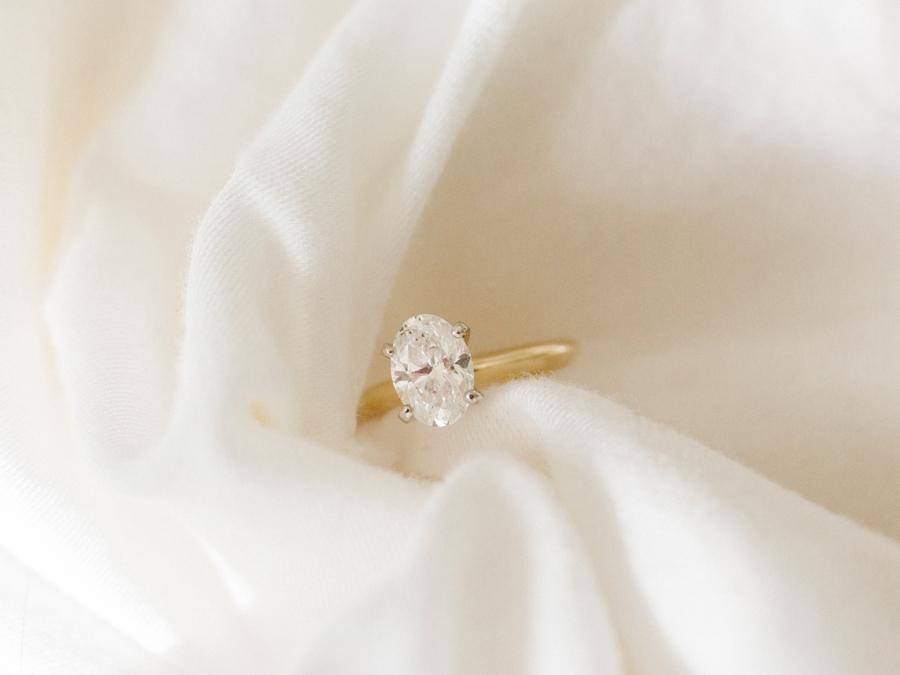 A oval solitaire engagement ring from an intimate in-home enagement session by Love Tree Studios.