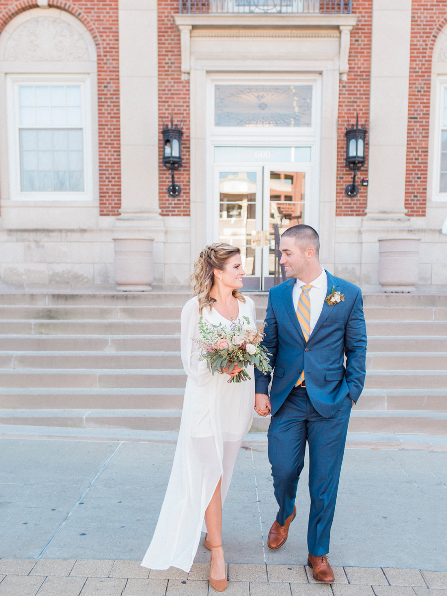 A bride and groom poses outside the courthouse in Columbia Missouri during their intimate courthouse wedding by wedding photographer Love Tree Studios.