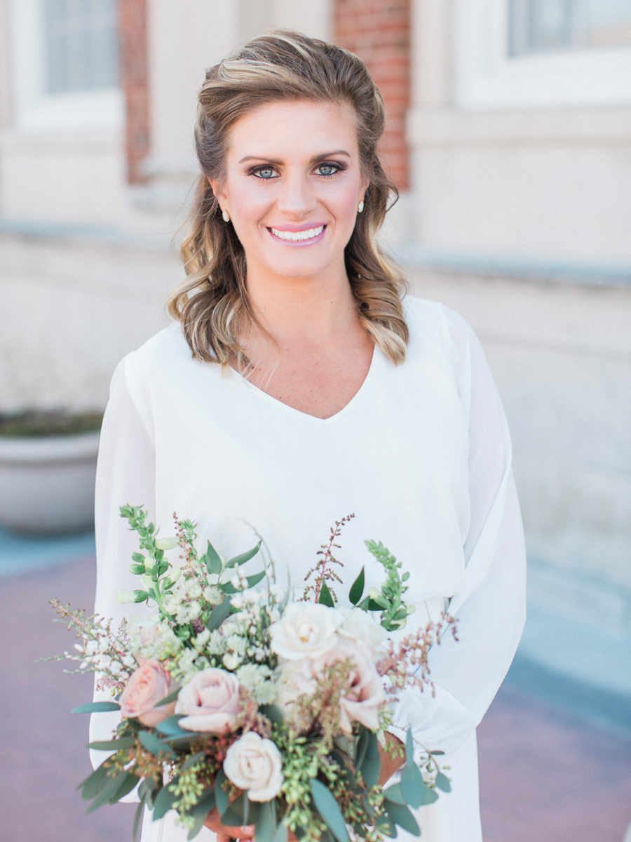 The bride poses with her bouquet by Sugarberry Blooms for a photo taken by wedding photographer Love Tree Studios at her intimate courthouse wedding..