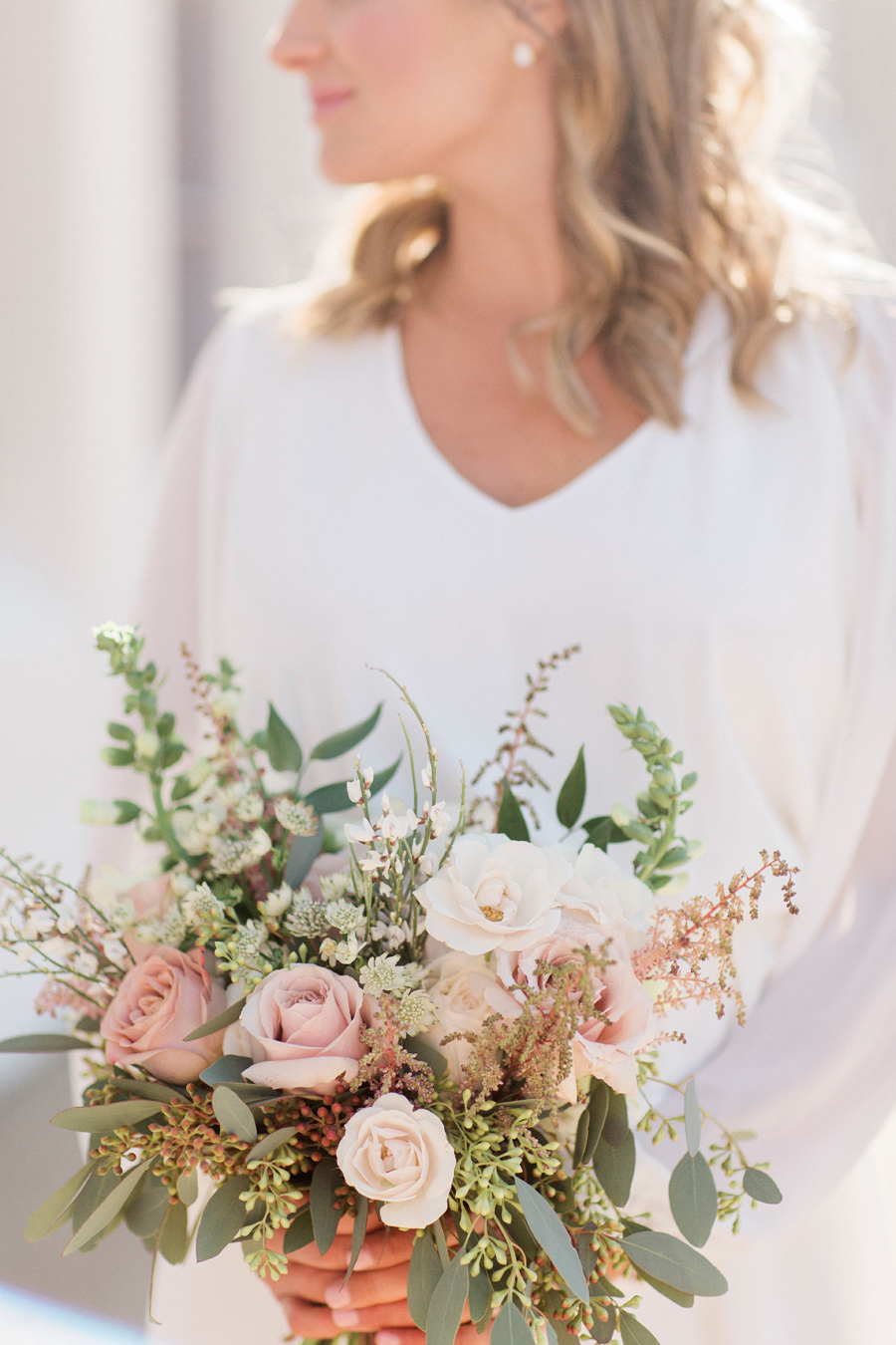 The bride poses with her bouquet by Sugarberry Blooms for a photo taken by wedding photographer Love Tree Studios at her intimate courthouse wedding..