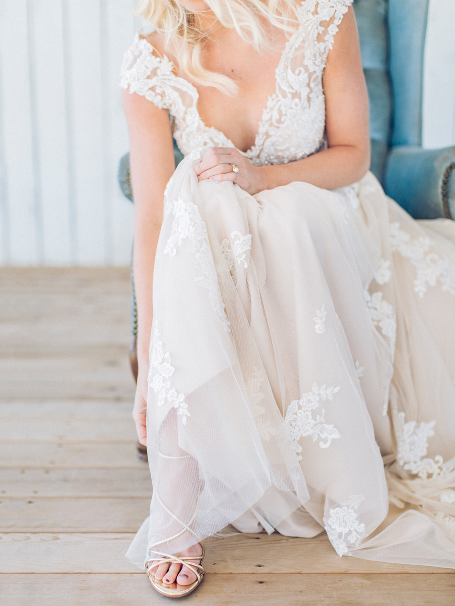 The bride puts on her shoes in her Morilee dress at a Missouri wedding by Love Tree Studios.