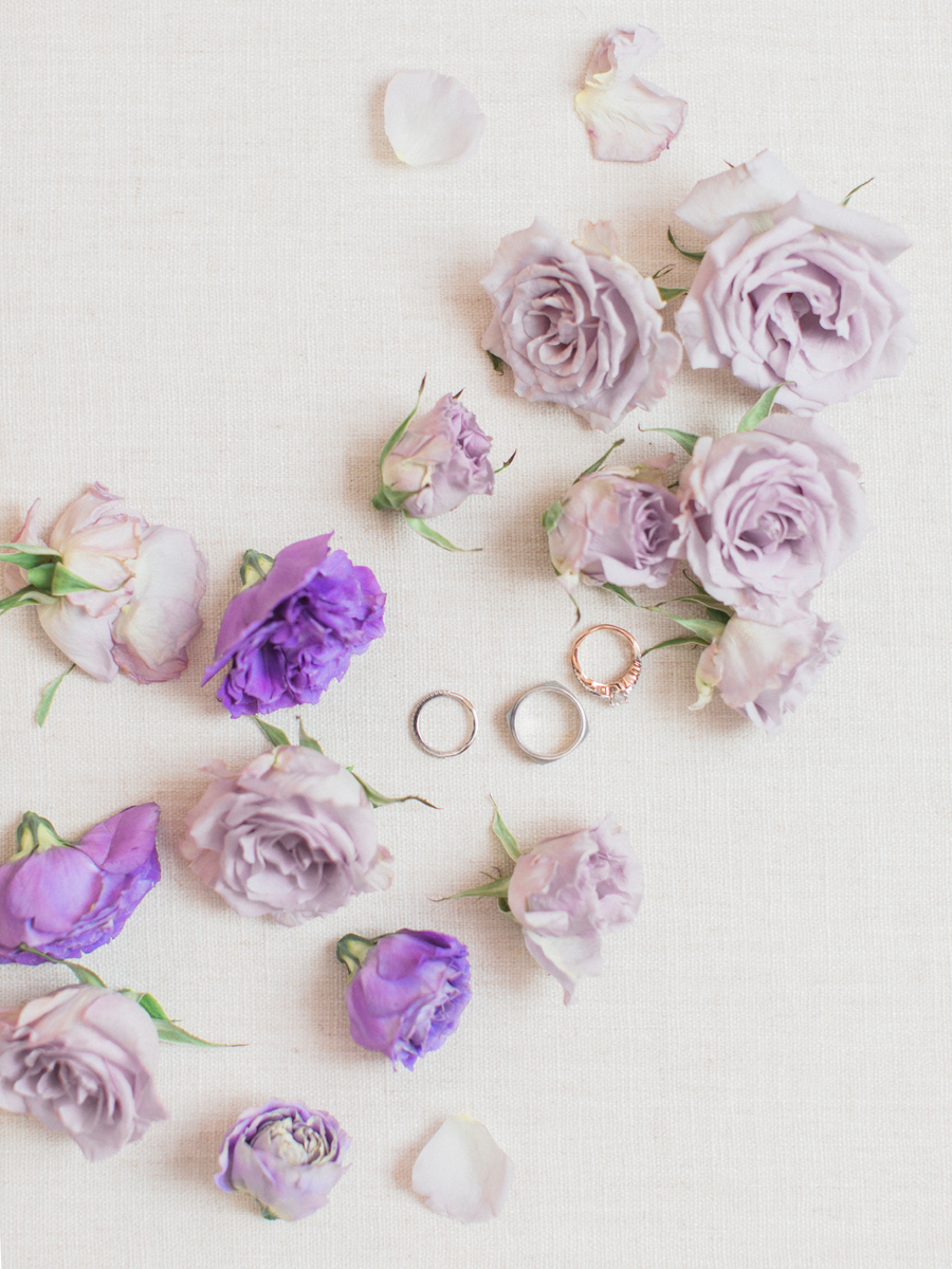 Wedding rings amid purple roses photographed by Love Tree Studios at a camdenton missouri wedding.