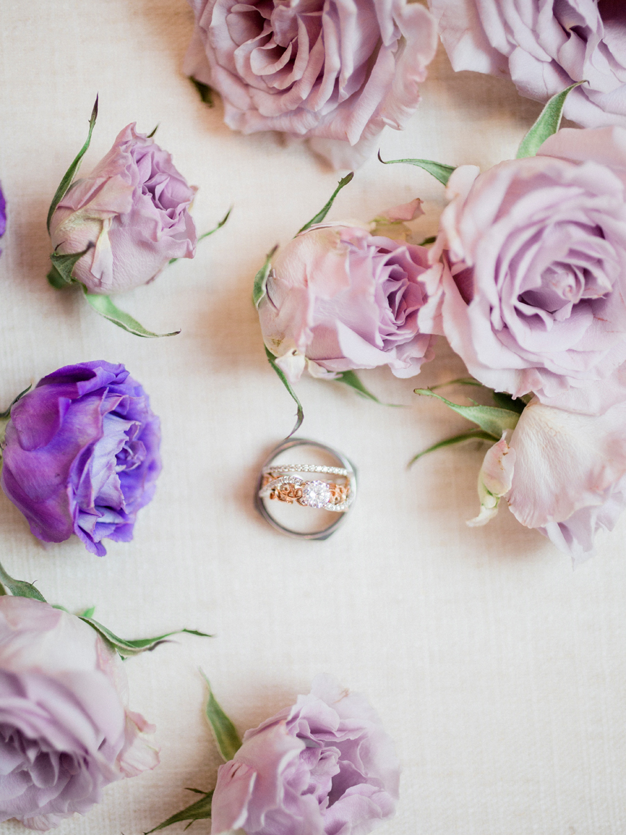 Wedding rings amid purple roses photographed by Love Tree Studios at a camdenton missouri wedding.