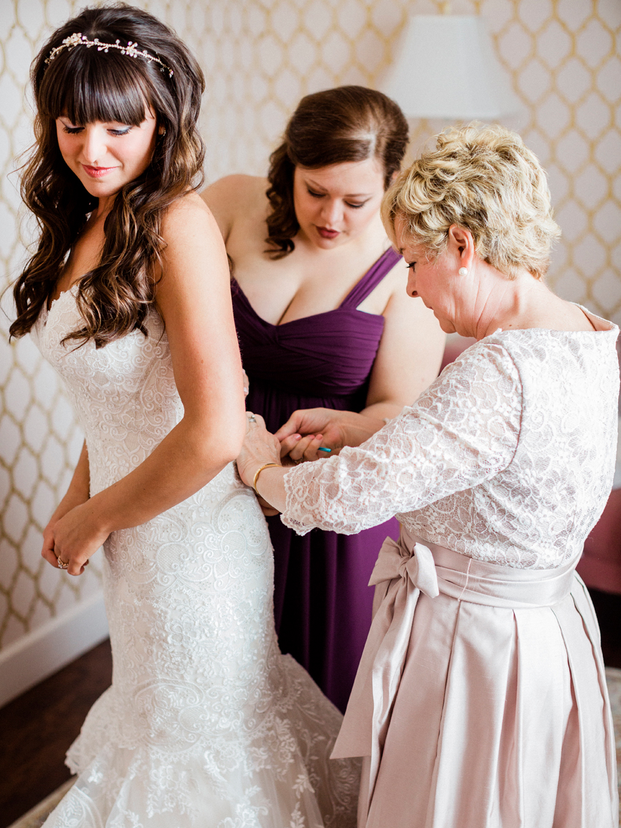 A bride puts her dress on at The Exchange Venue while being photographed by fine art wedding photographer Love Tree Studios at a Camdenton Missouri wedding.