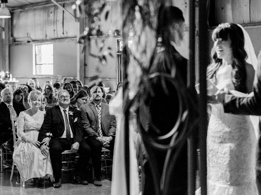 Wedding photographer Love Tree Studios captures parents looking on during the wedding ceremony at The Exchange Venue at a Camdenton Missouri wedding.