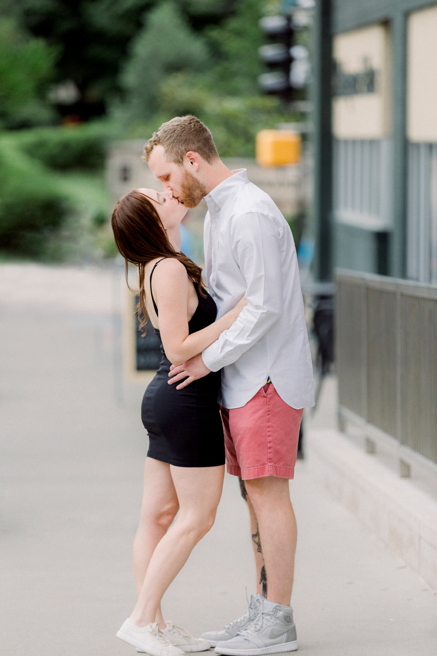 A couple kisses on the sidewalk in front of Shakespeare's Pizza during their engagement session.