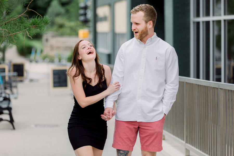 A couple laughs in front of Shakespeare's Pizza during their engagement session.