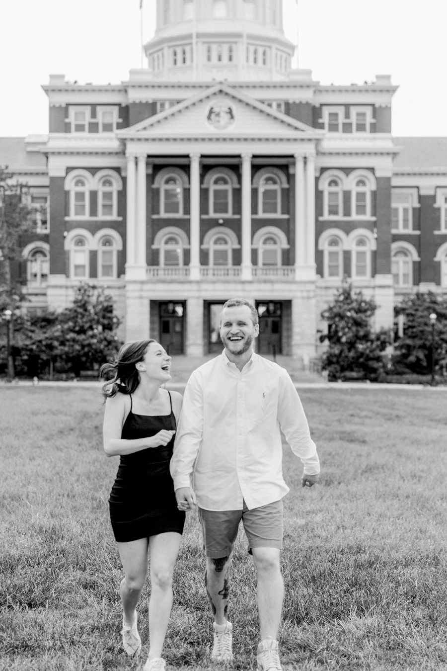 A laughing couple runs toward the camera for their University of Missouri engagement session.
