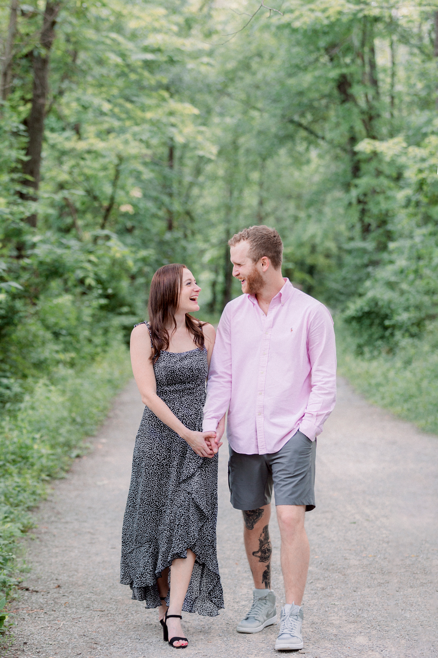 A couple walks hand in hand down the MKT trail during their engagement session.