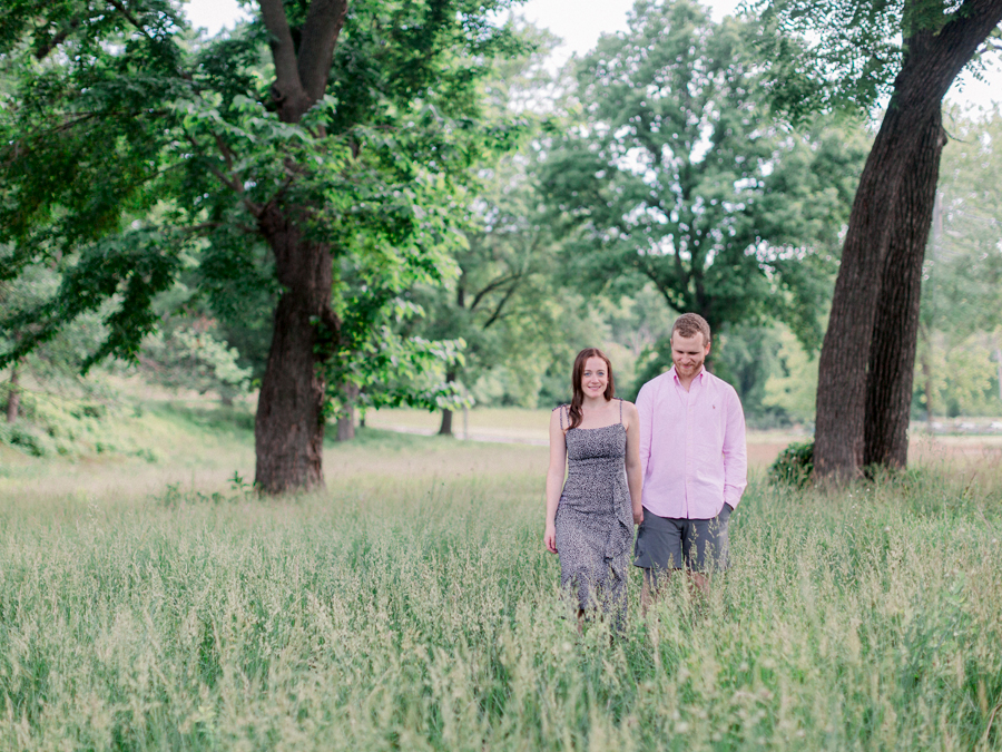 A girl leads a guy through a field for an outdoor engagement session in Columbia, Missouri.