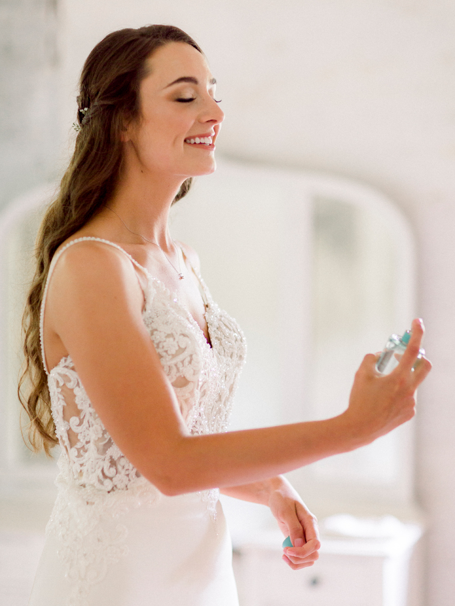 The bride sprays perfume in the bridal cottage at Wildcliff Weddings and Events.