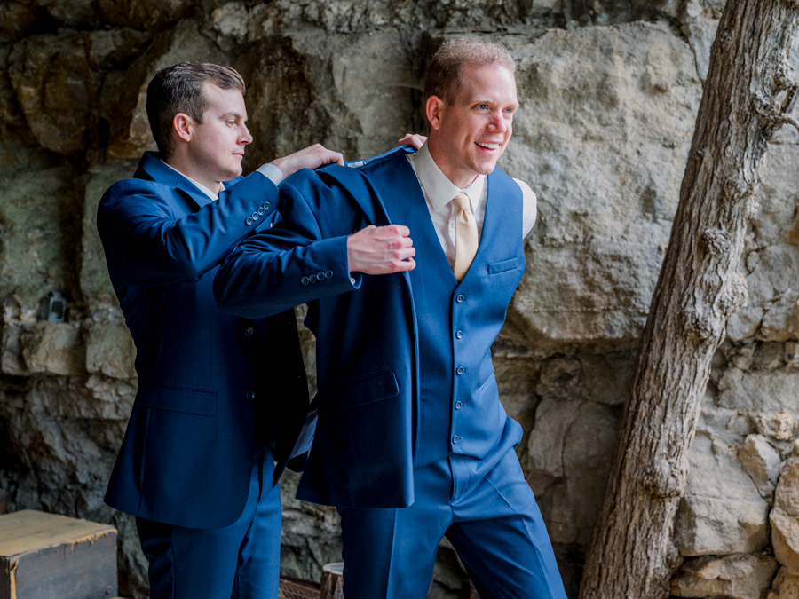 A groom puts his jacket on in the cave at Wildcliff Weddings in Blackwater, Missouri.