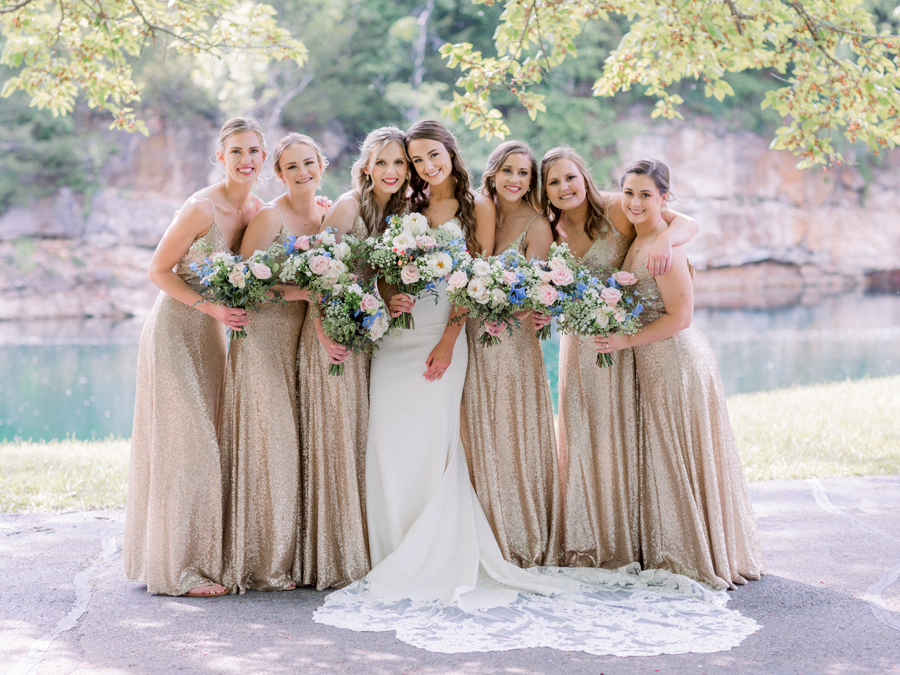 A bride poses with her bridesmaids in front of the water and cliffs at Wildcliff Weddings and Events.