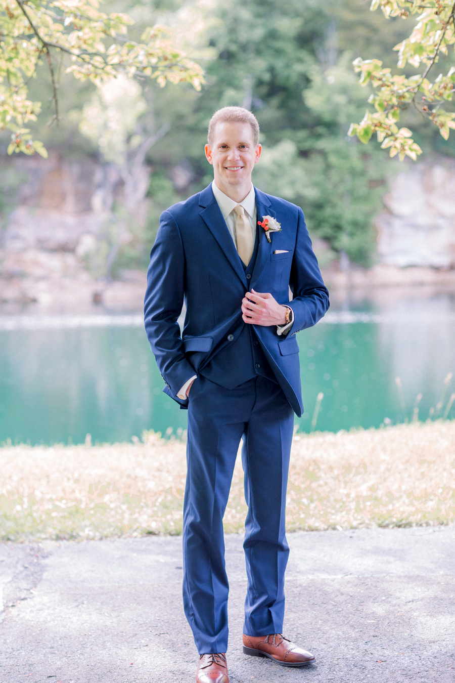 A groom poses in front of the water and cliffs at Wildcliff Weddings and Events.