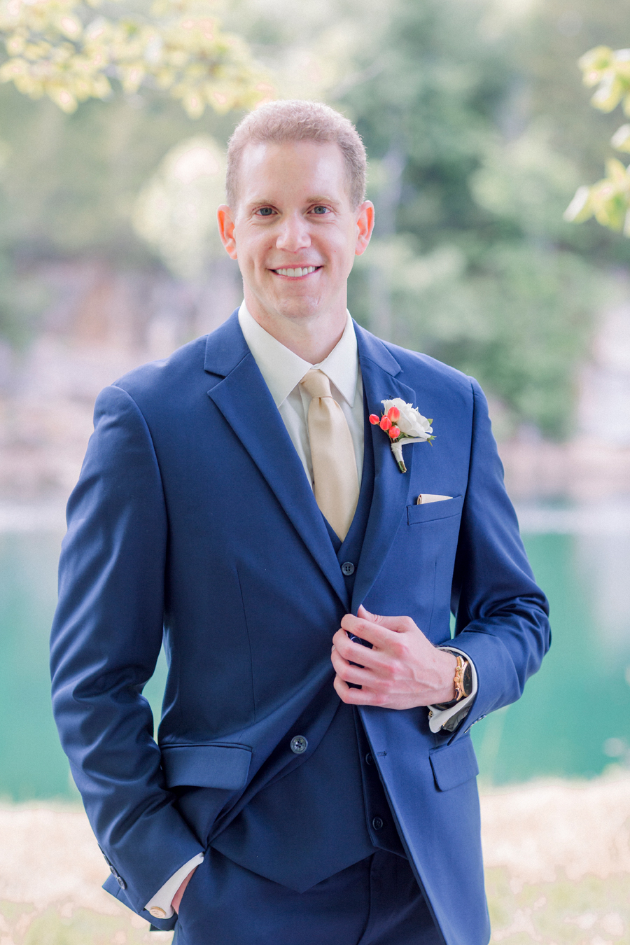 A groom poses in front of the water and cliffs at Wildcliff Weddings and Events.