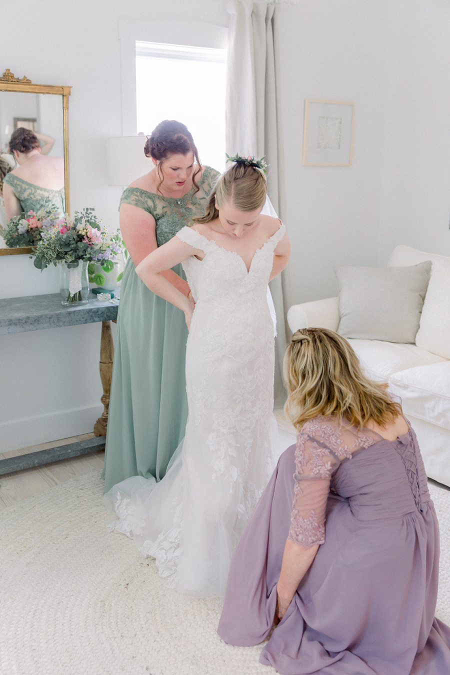 A bride puts her wedding dress on in the bridal suite at a Blue Bell Farm wedding by Love Tree Studios.