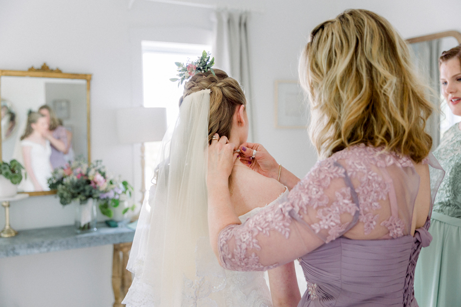 The bride's mother puts a necklace on the bride at a Blue Bell Farm wedding by Love Tree Studios.