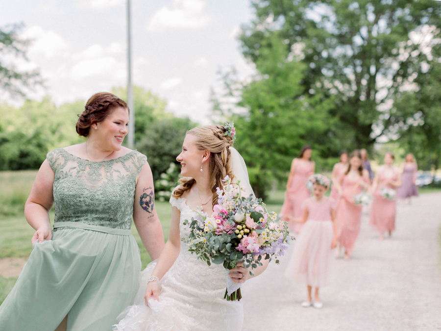 A bride and her bridesmaids walk on the grounds at a Blue Bell Farm wedding by Love Tree Studios.