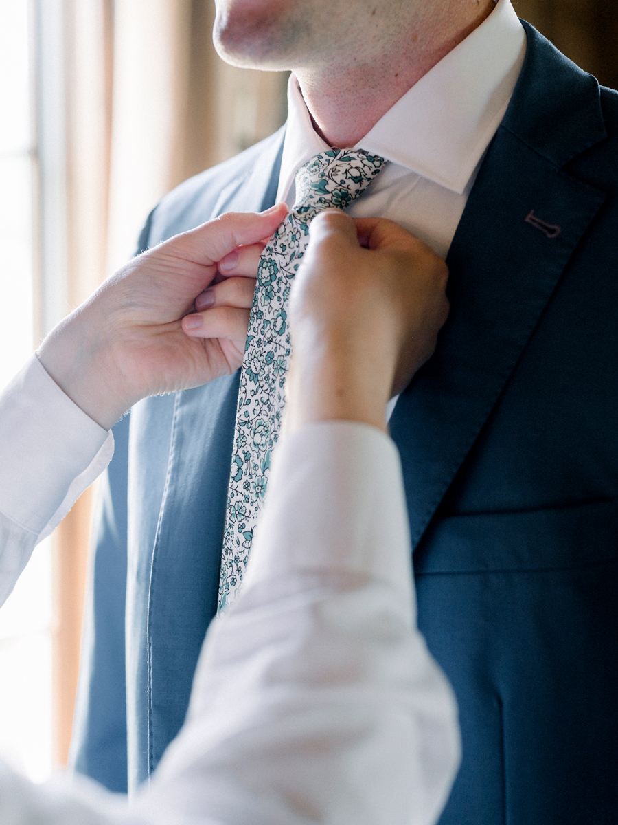 The groom ties his tie at a Blue Bell Farm wedding by Love Tree Studios.