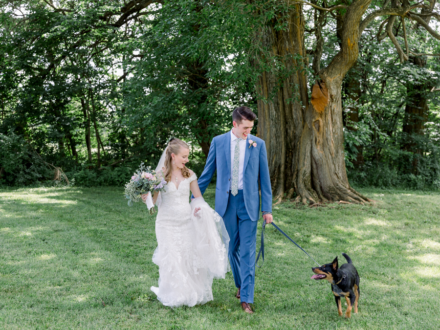 A bride and groom walk with their dog at a Blue Bell Farm wedding by Love Tree Studios.