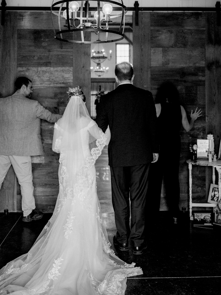 The barn doors are open as the bride prepares to walk down the aisle at a Blue Bell Farm wedding by Love Tree Studios.