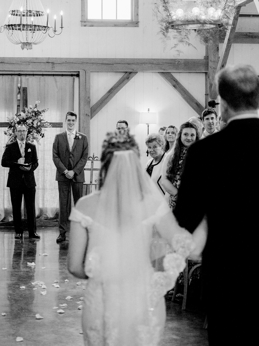 The groom smiles at the bride as she walks down the aisle at a Blue Bell Farm wedding by Love Tree Studios.