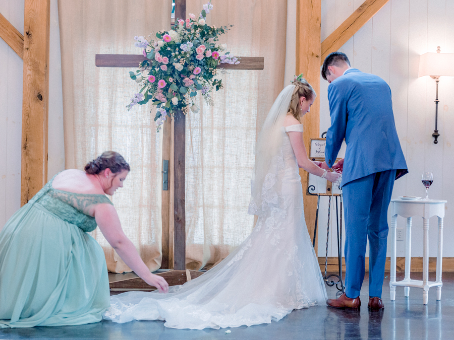 The maid of honor adjusts the bride's dress at a Blue Bell Farm wedding by Love Tree Studios.