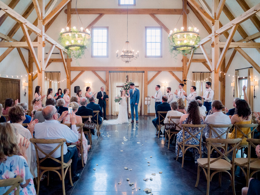 The bride and groom walk down the aisle in the barn at a Blue Bell Farm wedding by Love Tree Studios.