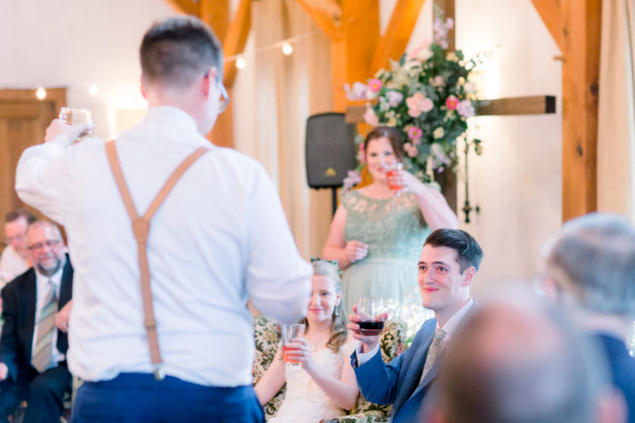Glasses are raised during toasts at a Blue Bell Farm wedding by Love Tree Studios.
