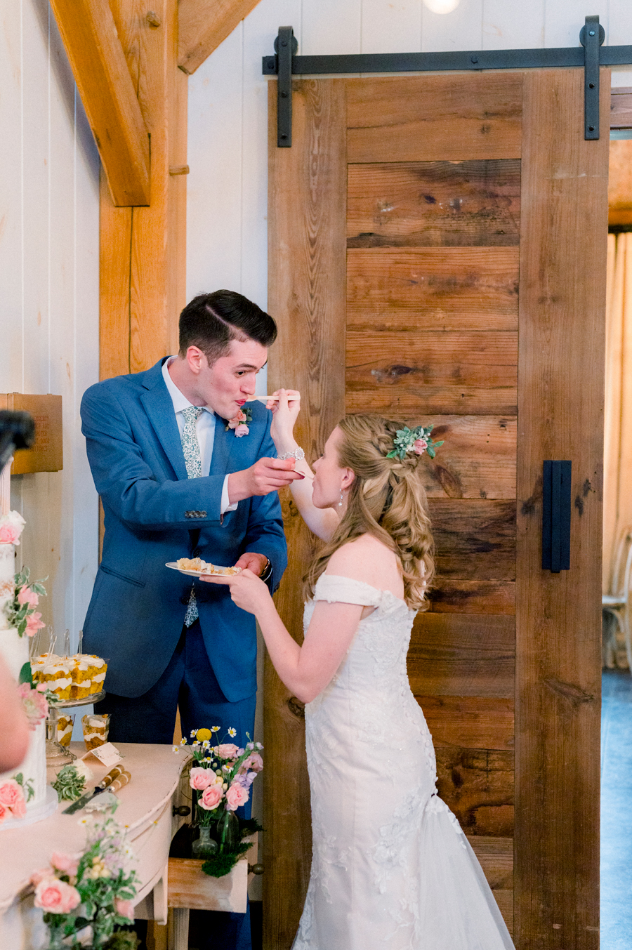 The wedding couple eats the cake at a Blue Bell Farm wedding by Love Tree Studios.