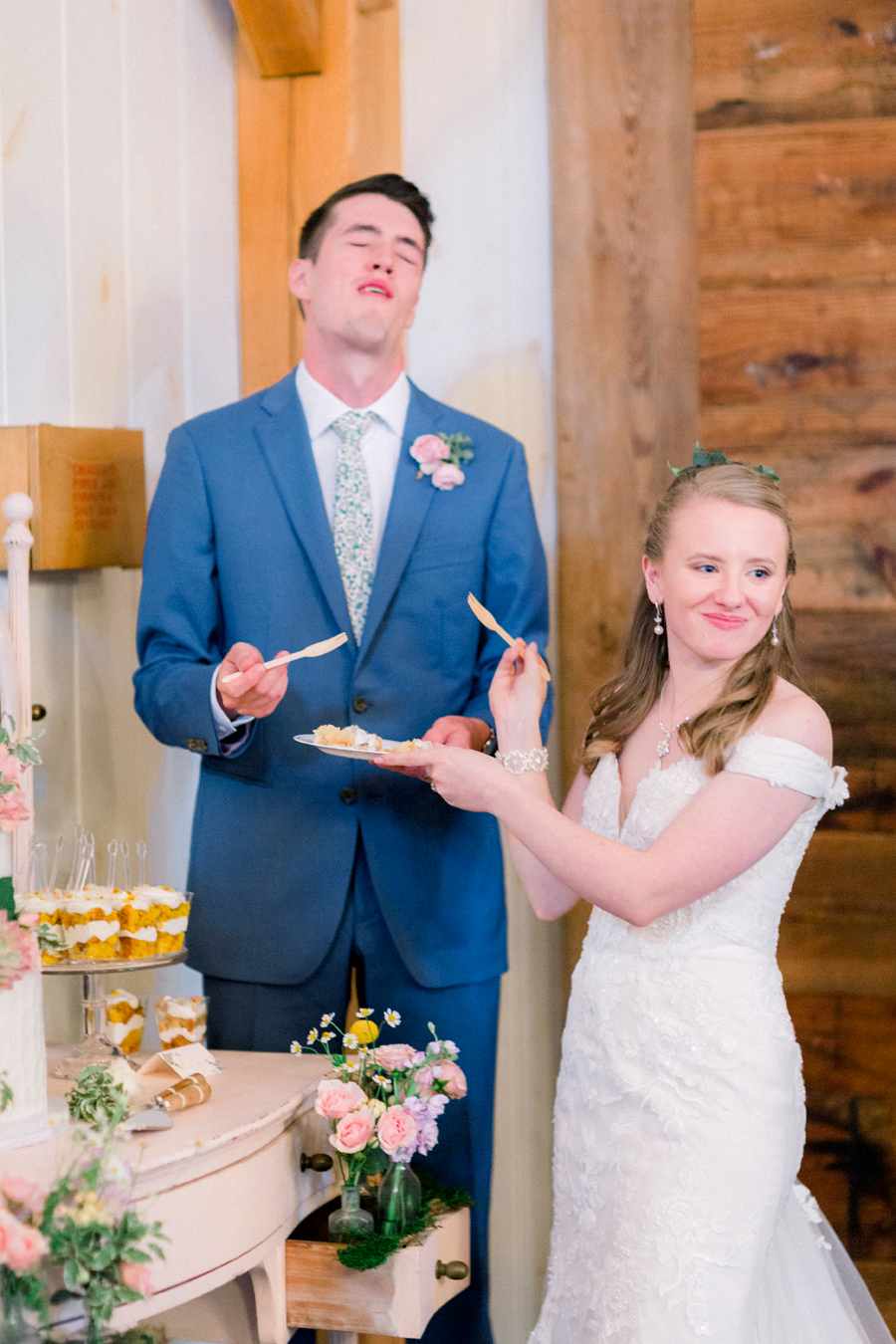 The bride smiles at guests as she tries the cake at a Blue Bell Farm wedding by Love Tree Studios.