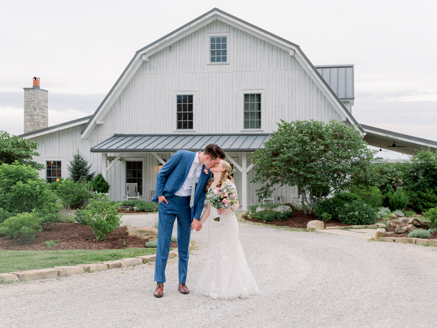 The bride and groom kiss in front of the barn at a Blue Bell Farm wedding by Love Tree Studios.