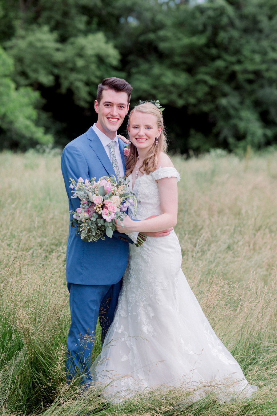 A bride and groom take portraits in the field at a Blue Bell Farm wedding by Love Tree Studios.