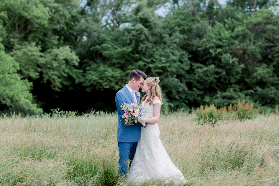 The bride and groom stand in the fields at a Blue Bell Farm wedding by Love Tree Studios.