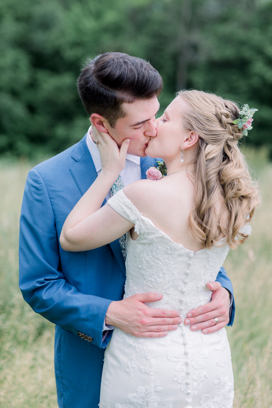 The bride kisses the groom in a field at a Blue Bell Farm wedding by Love Tree Studios.