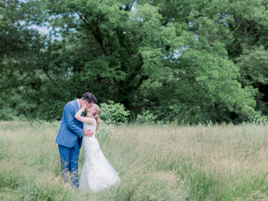 A couple kisses in the field at a Blue Bell Farm wedding by Love Tree Studios.