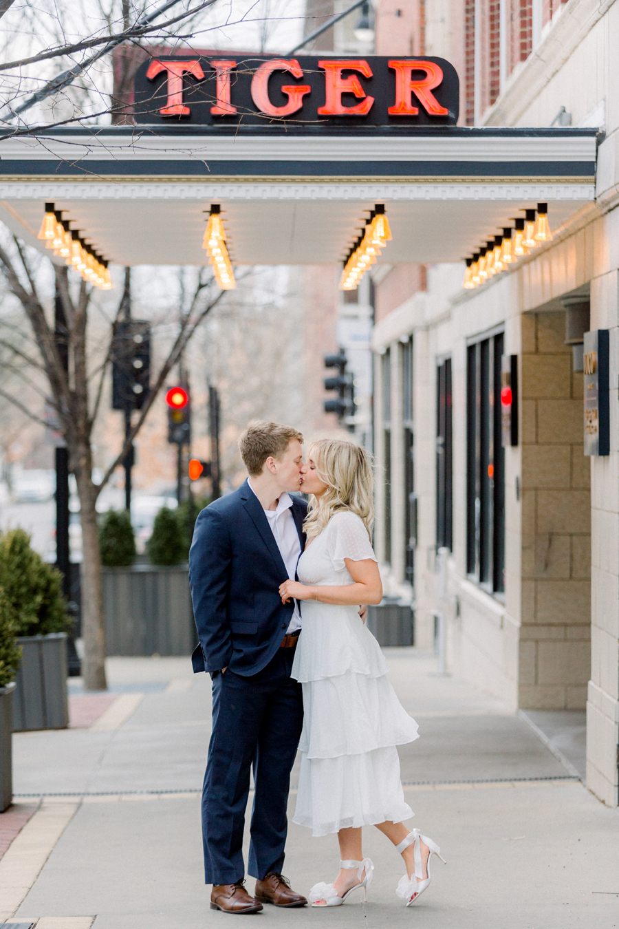 A couple takes photos in front of Tiger Hotel for their engagement session in downtown Columbia, Missouri by Love Tree Studios.