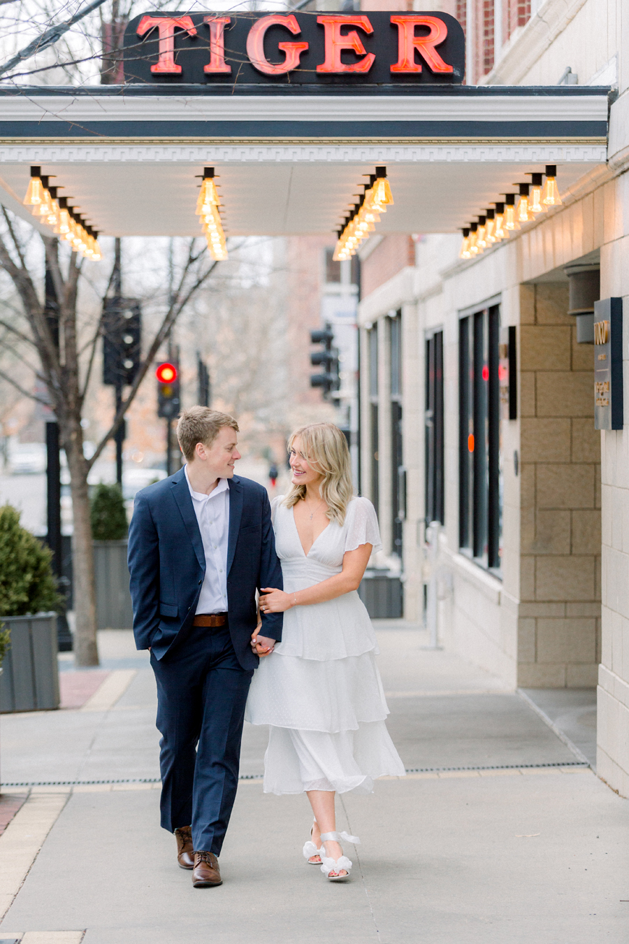 A couple takes photos in front of Tiger Hotel for their engagement session in downtown Columbia, Missouri by Love Tree Studios.