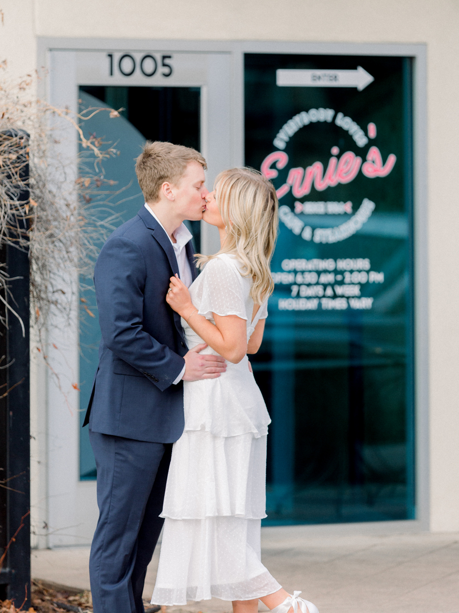 A couple takes photos in front of Ernie's Cafe for their engagement session in downtown Columbia, Missouri by Love Tree Studios.