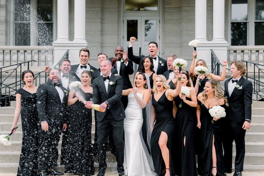 A wedding party sprays champagne before for their Stephens College wedding photographed by Columbia, Missouri wedding photographer Love Tree Studios.