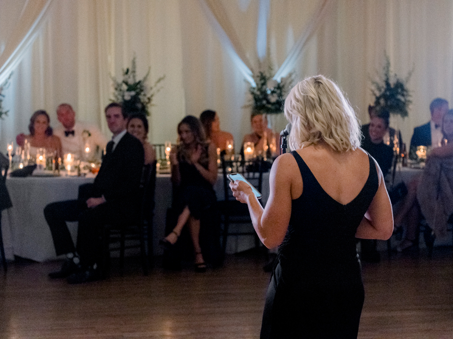A bride and groom hear toasts during their wedding reception in Kimball Ballroom at their Stephens College wedding photographed by Columbia, Missouri wedding photographer Love Tree Studios.