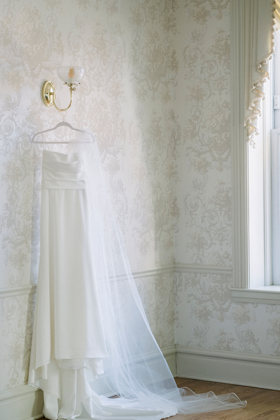 The bride's dress hangs on the wall ready for her elegant Stephens College wedding photographed by Columbia, Missouri wedding photographer Love Tree Studios.