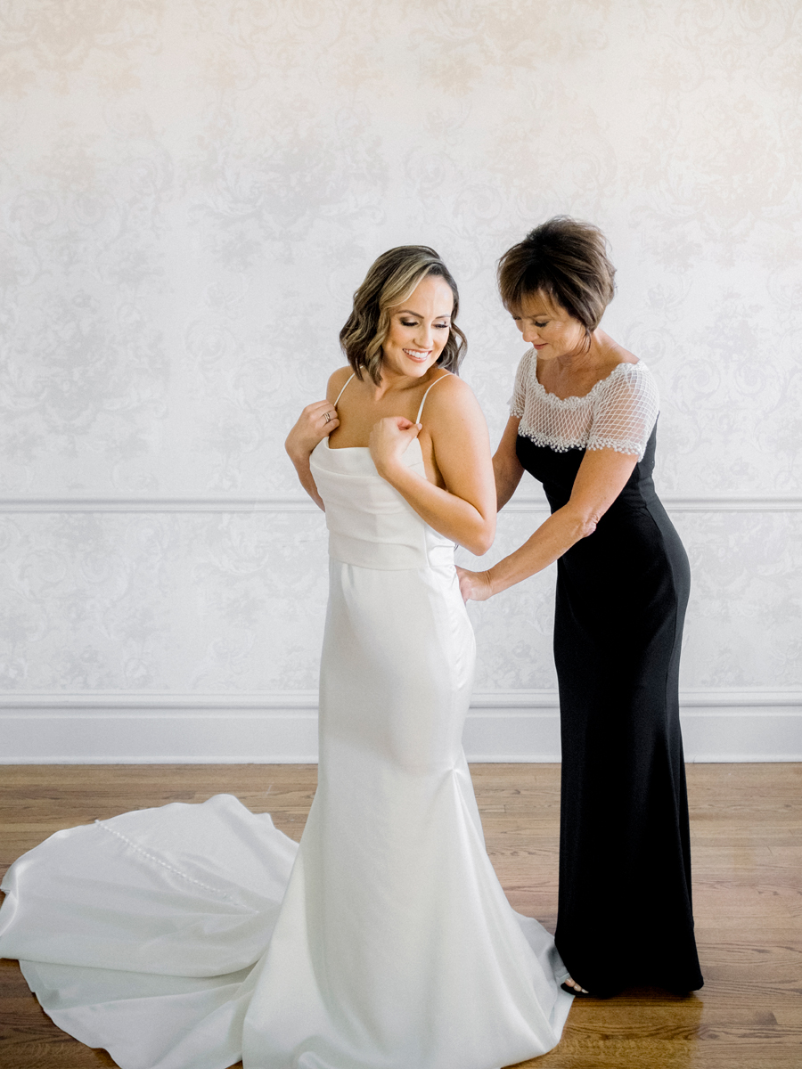 A bride puts on her wedding dress in preparation for her Stephens College wedding photographed by Missouri wedding photographer Love Tree Studios.