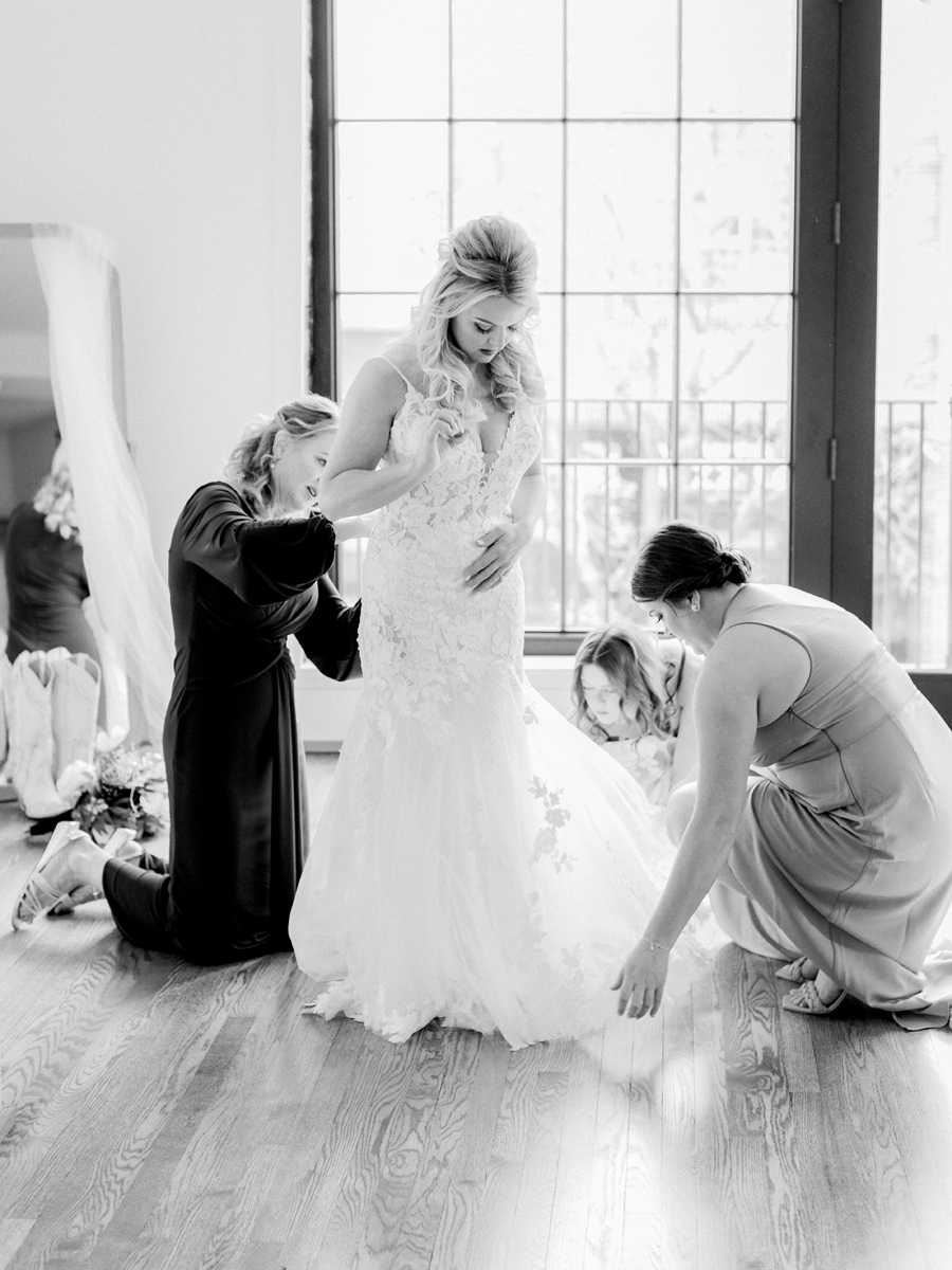 The bride puts on her wedding dress for her Atrium on Tenth wedding in Columbia, Missouri by Love Tree Studios.