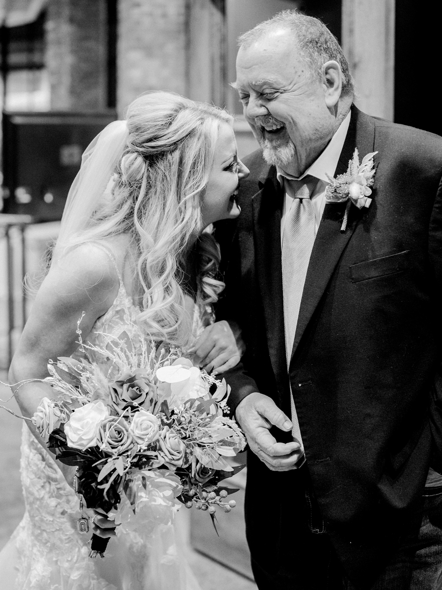 A bride laughs with her father before walking down the aisle at her wedding at Atrium on Tenth wedding in Columbia, Missouri by Love Tree Studios.