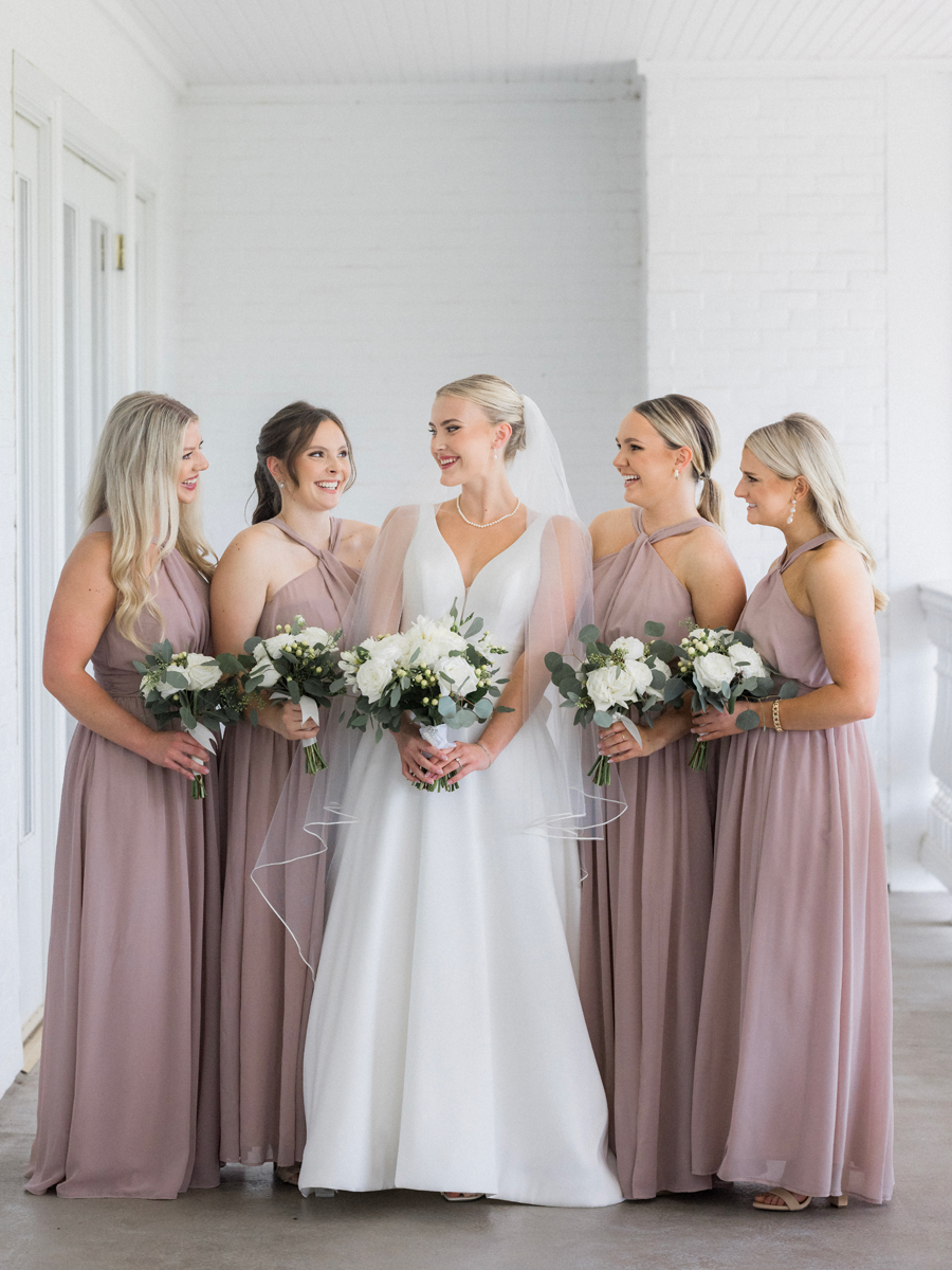 The bride poses with her bridesmaids at the Club at Old Hawthorne for a Westminster College wedding by Love Tree Studios.