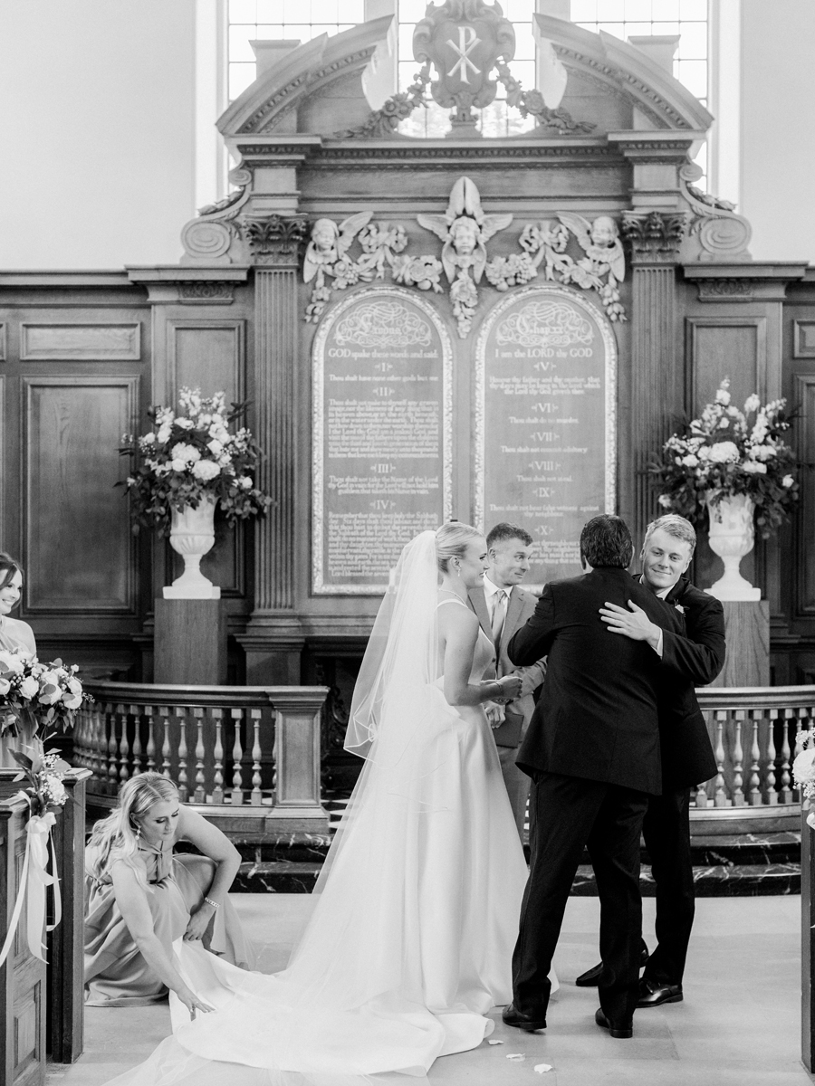 The bride's father gives her away at the altar in the Church of St. Mary, Aldermanbury at a Westminster College wedding by Love Tree Studios.